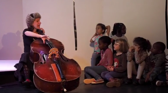 enfants écoutant une artiste jouant du violoncelle